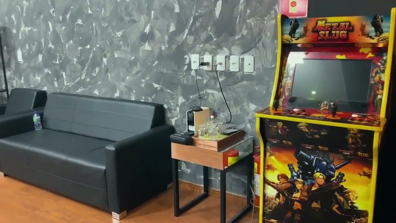 Lounge da Vegas Barbearia com sofá, mesa de apoio e fliperama