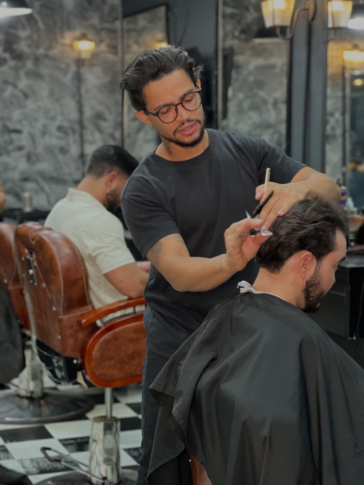 Salão da Vegas Barbearia visto pelo espelho, com cadeiras e bancada