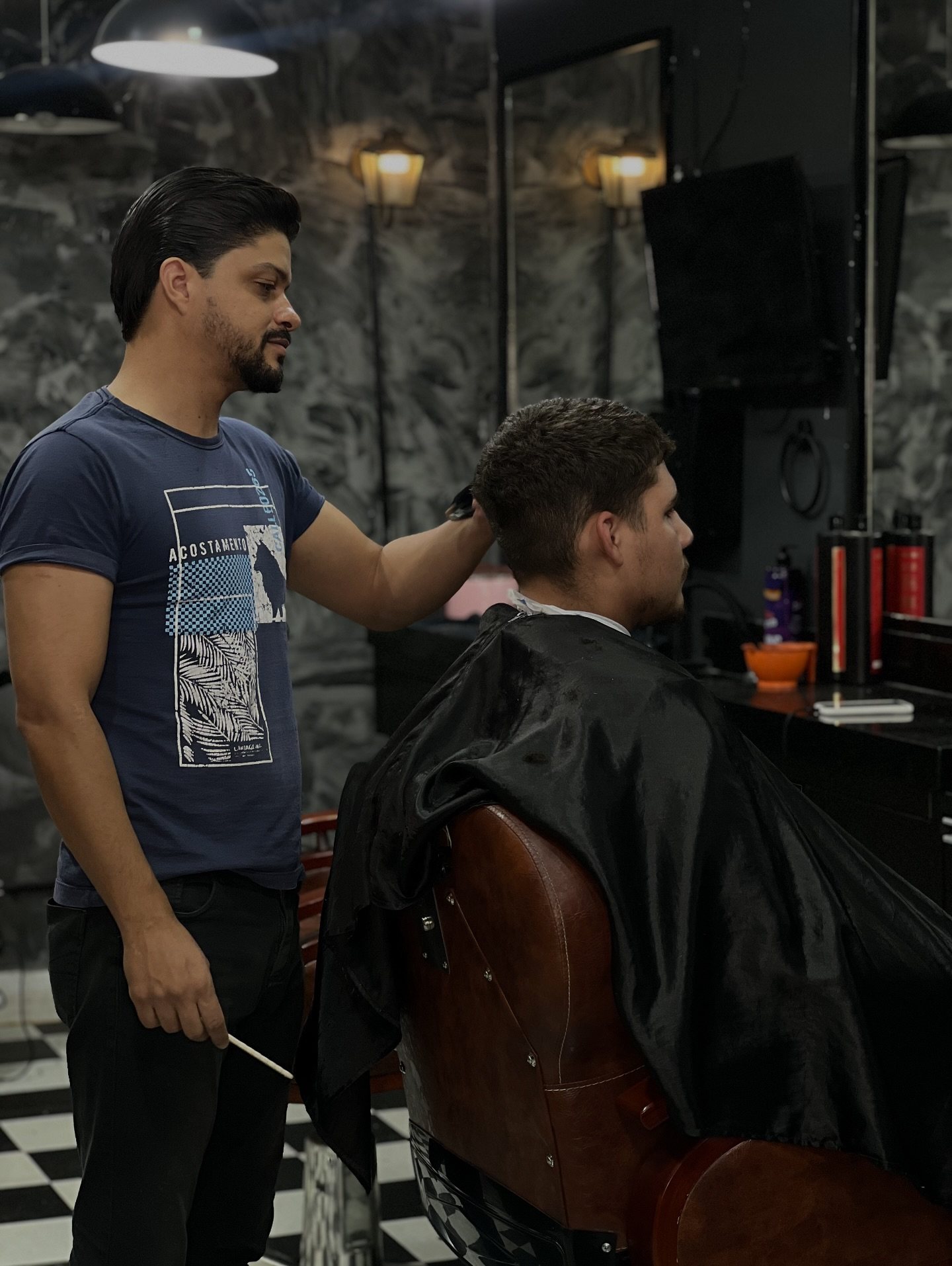 Parede de pedra e cadeira de barbeiro na Vegas Barbearia